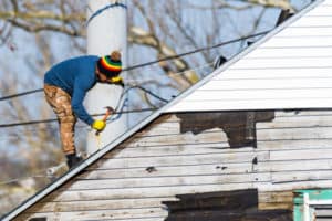 repairing roof shingles with a hammer