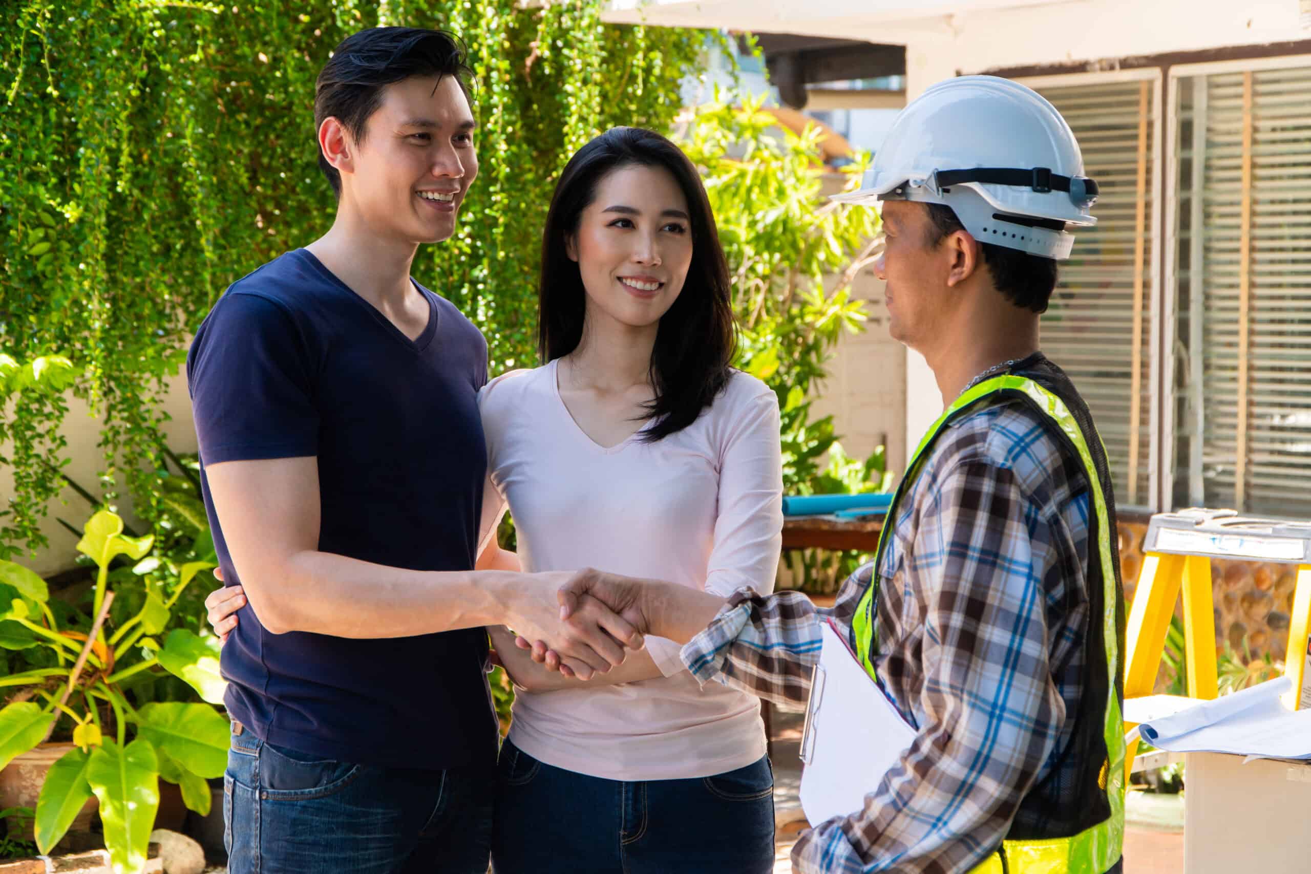 Happy homeowner stand in front of contractor and shake hand, handyman holding clipboard and after checking details before renovations home, house improvement exterior, exterior design